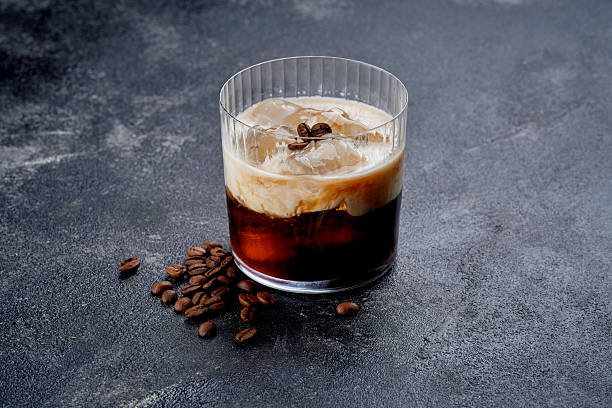 Iced cold brew with cream in a glass beside coffee beans