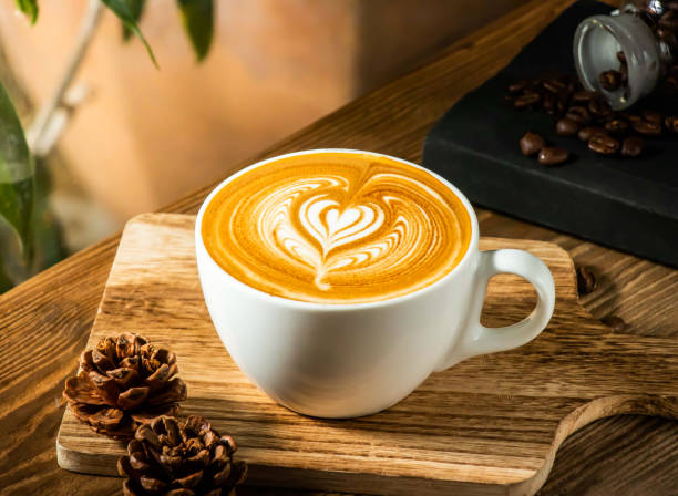 Heart latte art in a white cup on a wooden board